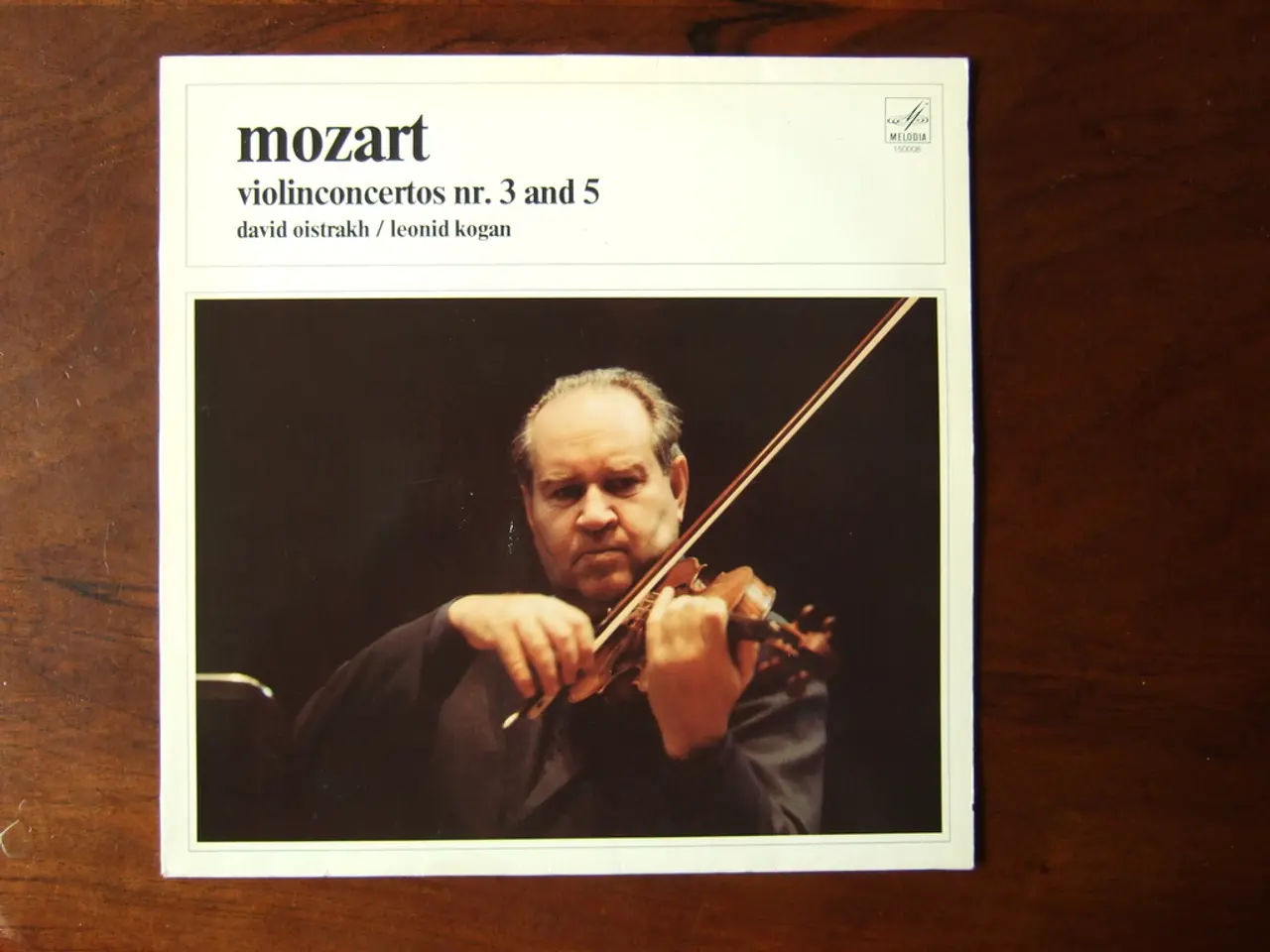 In this picture there is a photograph placed on a wooden table. In the front we can see a man...