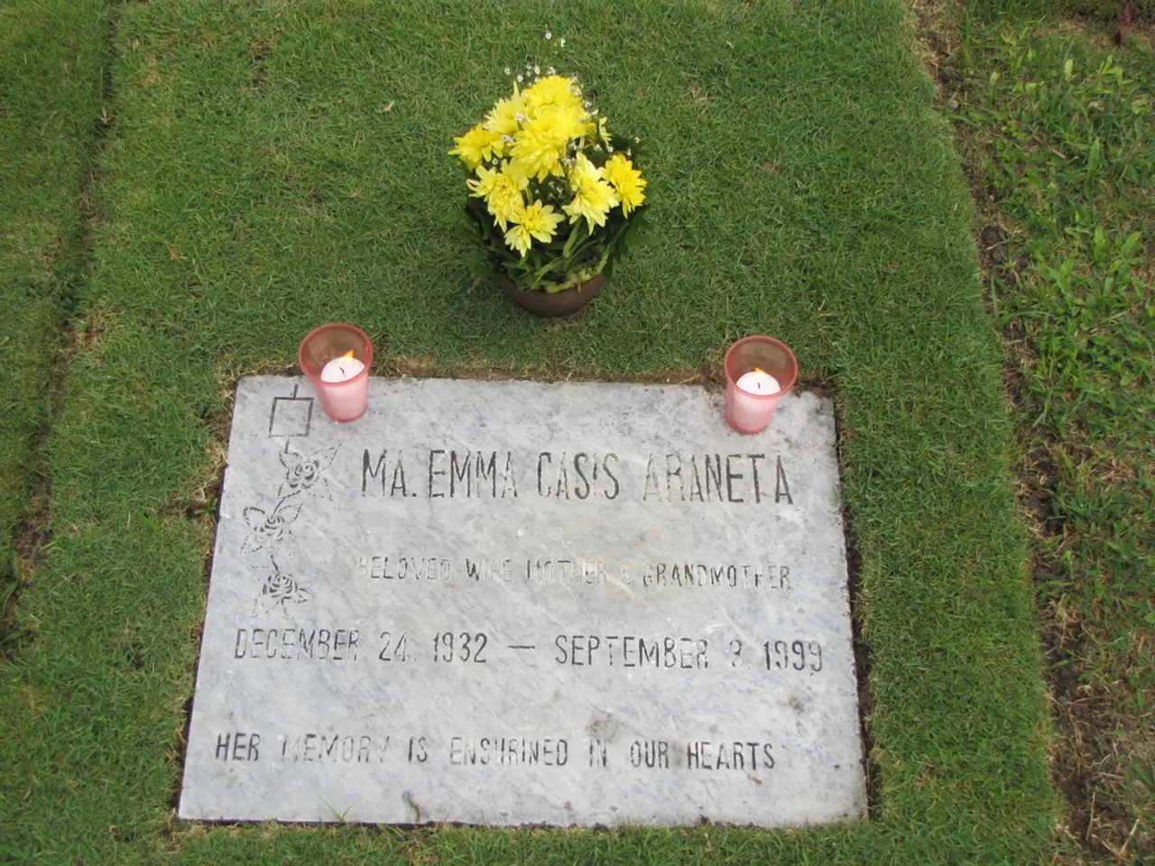 In this picture we can see a tombstone. On the tombstone, there are two glasses and in the glasses...