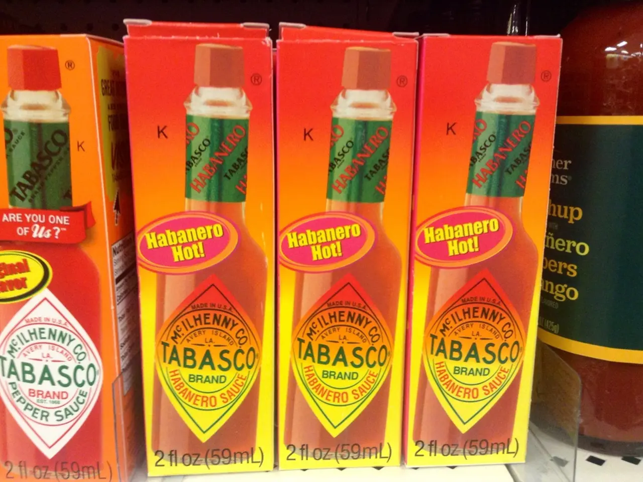 In the image we can see there are sauce bottle boxes kept on the rack and there is another sauce...
