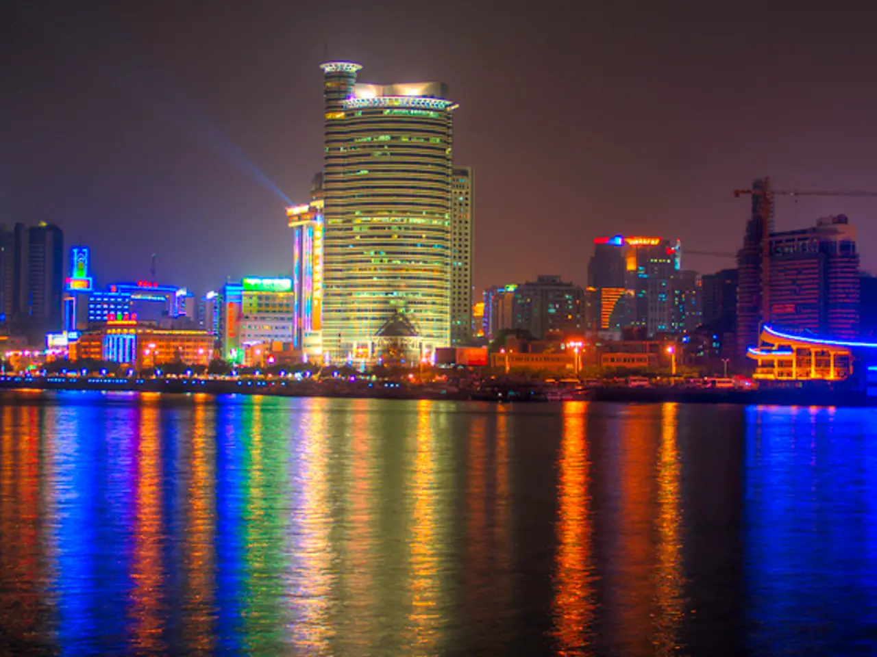 At the bottom of the image there is water. In the middle of the image there are some buildings and...