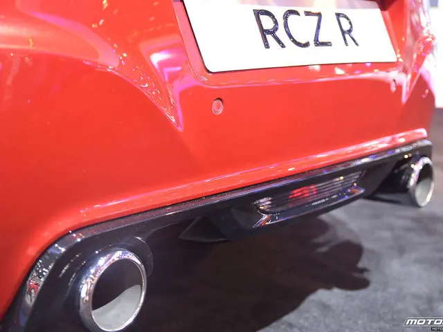 In this picture we can see a red color car. There is a number plate on this car. We can see a...