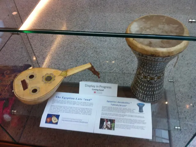 In this image we can see musical instrument are kept in a glass rack. And name plate and paper is...