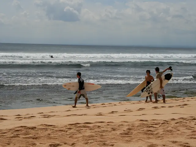 This is the picture where have three people holding the rowboats and standing on the sand near the...